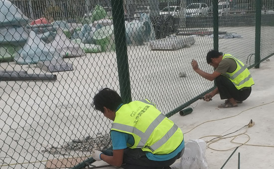 施工人员在安装塑胶篮球场围网